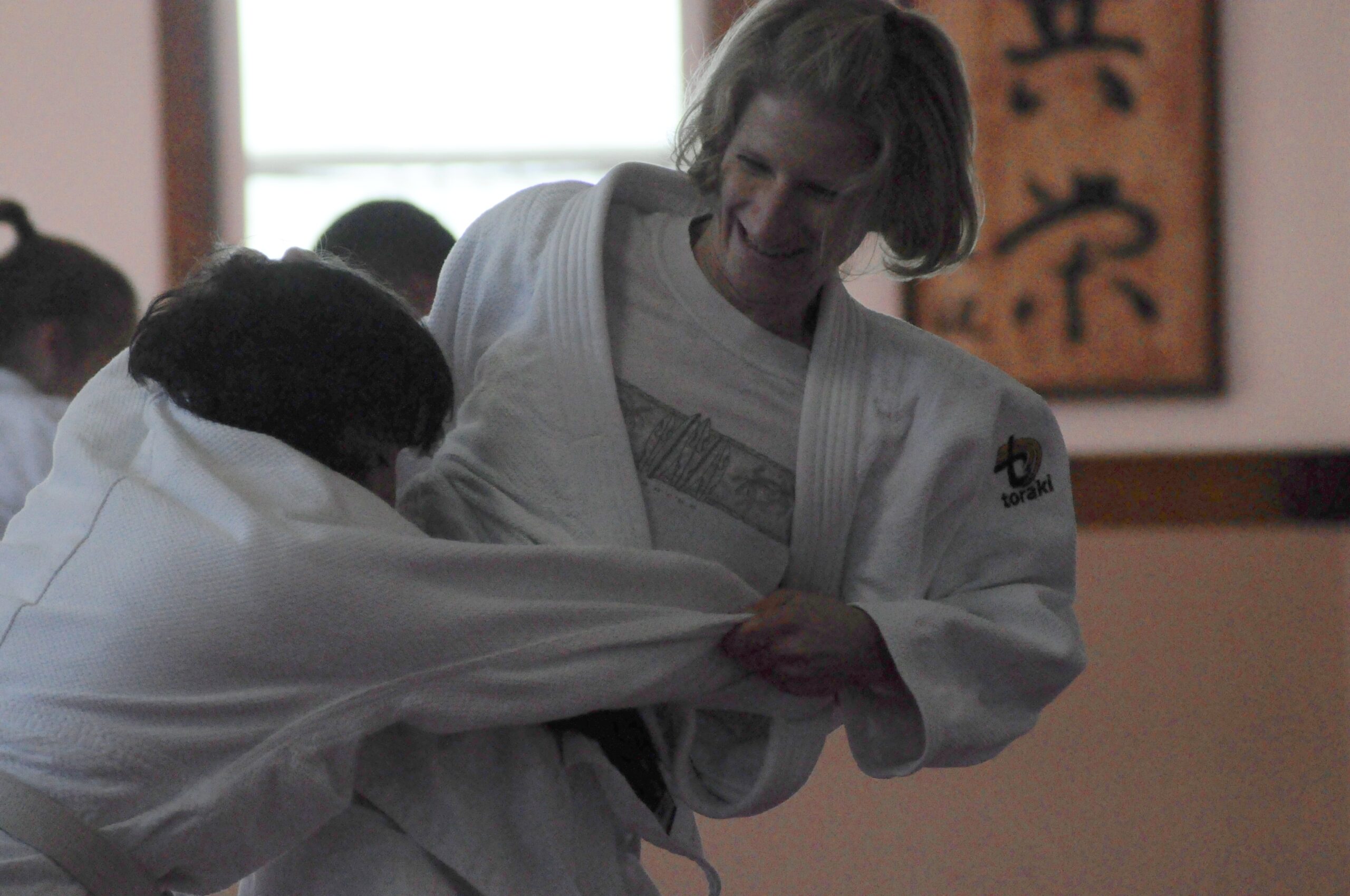 Deux personnes vêtues d’un kimono blanc pratiquant le judo en intérieur.