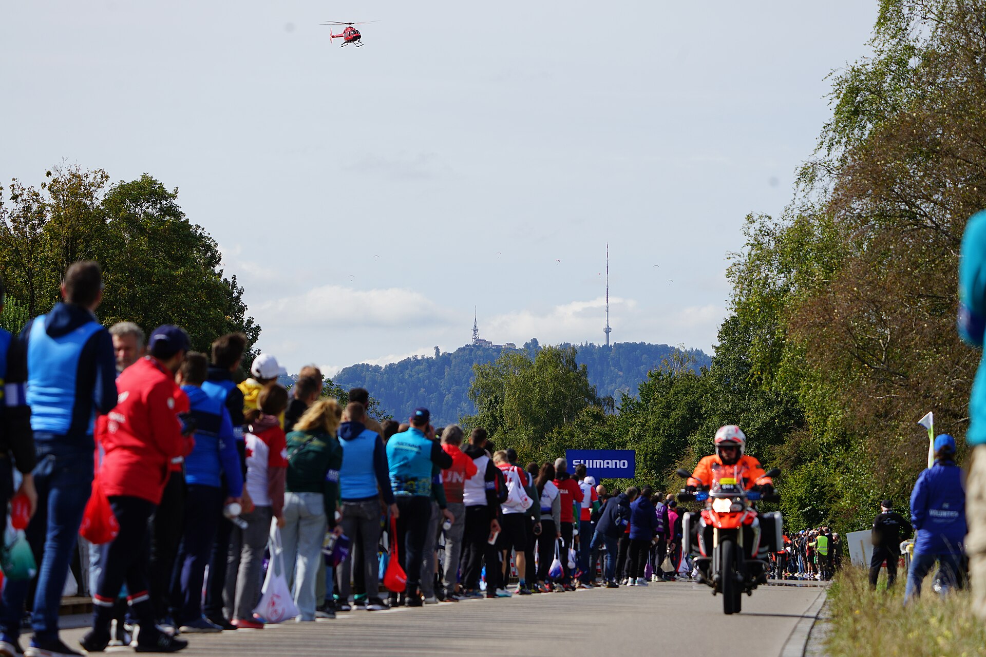 Moto de course ouvrant la route devant une longue haie de spectateurs